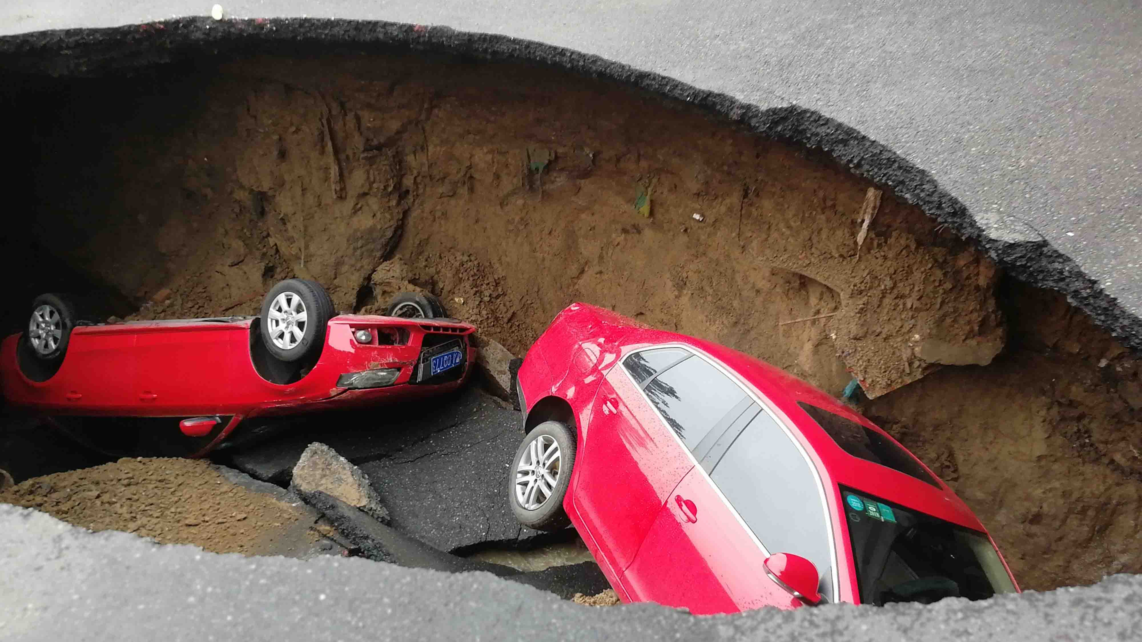 Two cars dropped into a sinkhole caused by a road collapse in northeast